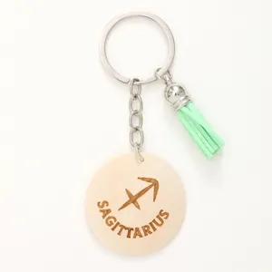 Dettaglio portachiavi legno Sagittario con nappa verde menta e simbolo zodiacale inciso