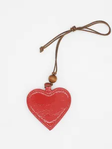 Close-up of a red heart-shaped PU leather glasses clip with a wooden bead detail.