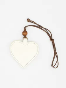Macro view of a cream heart-shaped PU leather glasses clip with a brown lanyard