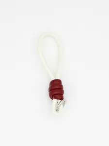 Detail showing white braided PU leather wrist strap with burgundy knot and metal ring
