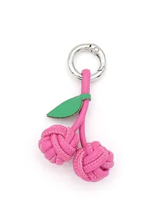 Macro view of a handcrafted pink woven PU leather cherry-shaped keychain with green leaf