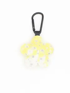 Detalle del llavero con colgante de flor con lentejuelas en cuadros amarillo y blanco