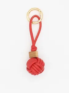Detailed macro view of red PU leather woven ball keychain with a natural wooden bead accent