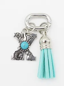 Close-up of ethnic style silver letter X charm with turquoise and aqua tassel.