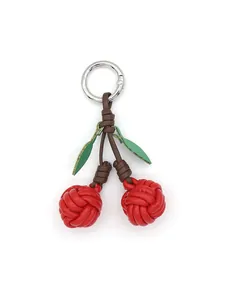 Detailed macro view of a handmade red PU leather woven cherry keychain and bag charm