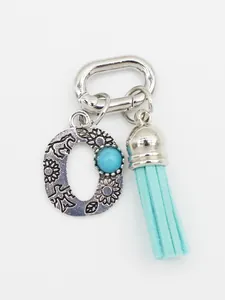 Close-up of bohemian letter O charm with turquoise bead and light blue tassel ornament.