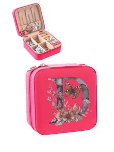 Detailed view of pink jewelry box with floral 'D' print and organized interior