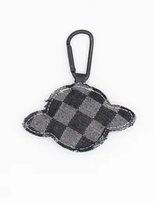 Close-up van planeetvormige denim sleutelhanger met zwart-wit geruit patroon