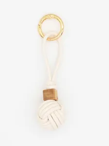 Close-up of a handmade white PU leather woven ball keychain with a rustic wood bead detail.