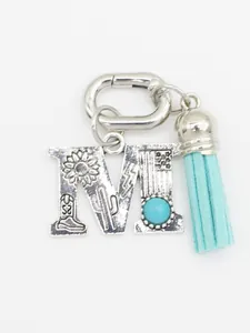 Detail of silver letter M charm with turquoise stone and light blue tassel