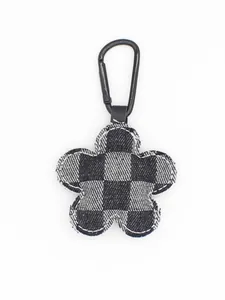Primer plano de un llavero de flor de mezclilla a cuadros con clip de metal negro para bolso