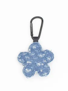 Primer plano de un llavero de flor en tela vaquera azul con lentejuelas plata