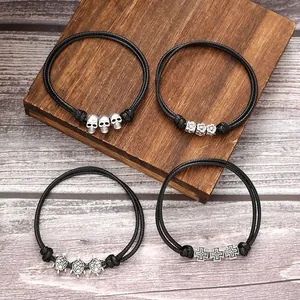 Close-up of four ethnic handmade woven bracelets featuring skull, turtle and cross silver charms.