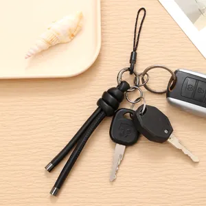 Minimalist black braided leather keychain strap shown attached to car keys on desk
