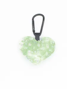 Detalle de un llavero de corazón de mezclilla verde con lentejuelas y clip negro