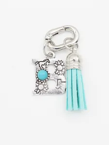 Close-up detail of vintage silver letter B charm featuring turquoise stone and teal tassel