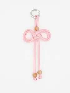 Detailed view of a hand-woven pink braided bow pendant with decorative beads and metal ring.