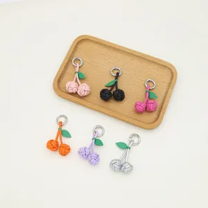 Handmade PU woven cherry ball keychains in multiple vibrant colors on wooden tray