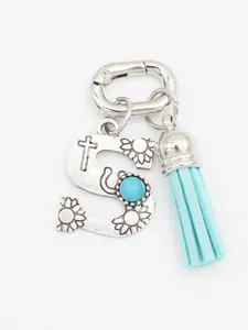 Detail view of ethnic style silver letter S pendant with turquoise and blue tassel