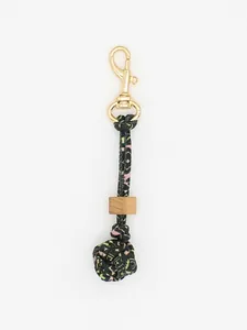 Macro detail of a handmade braided knot keychain with wooden bead and gold metal clasp