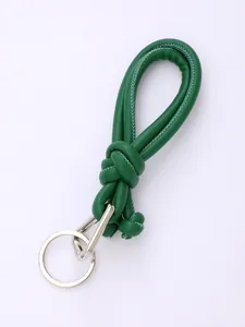 Detail of a handmade green braided PU leather keychain with silver metal ring and clasp.