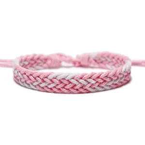 Macro view showing the intricate weave of a pink and white handmade braided wax rope bracelet