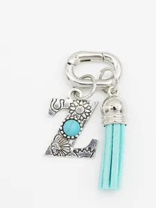 Macro view of bohemian silver letter Z bag charm with turquoise stone and blue tassel