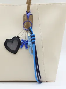 Heart-shaped leather mirror charm with blue bow and braided cord handbag accessory