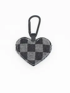 Primer plano de un llavero con forma de corazón y patrón de cuadros negro y gris