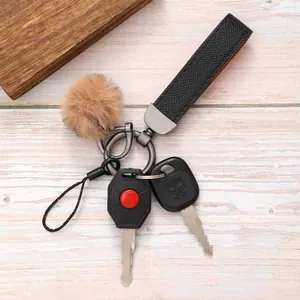 Nahaufnahme eines schwarzen Leder-Schlüsselanhängers mit braunem Plüsch-Pompon
