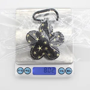 Medida de peso de un llavero de flor de tela negra con estrellas que pesa 8,02 gramos