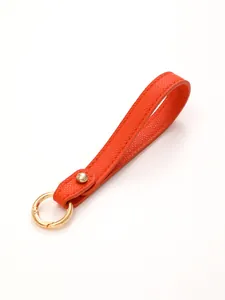 Close-up of bright orange pebbled leather wristlet keychain strap with gold ring