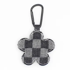 Llavero de flor de mezclilla a cuadros con mosquetón negro sobre fondo blanco, accesorio