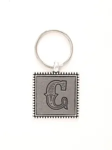 Detail view of the artistic letter C embossed on a grey leather and silver keychain