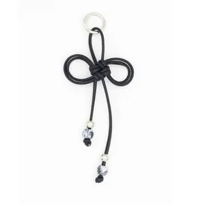 Handcrafted braided black PU rope bow keychain with marble-patterned beads and silver ring.