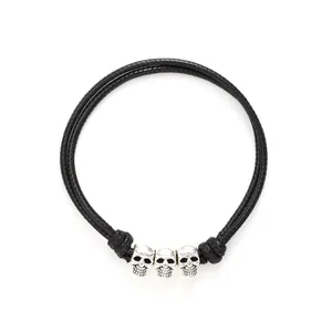 Black braided leather cord bracelet with three silver skull charms for gothic style