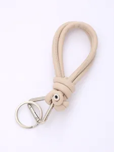 Detailed macro view of beige hand-woven PU leather phone lanyard with silver metal clasp