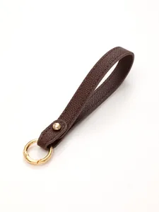 Detailed macro view of the premium brown leather texture on a stylish hand strap keychain.