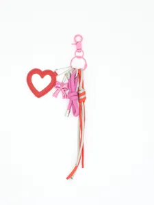 Detail of handmade woven bag charm with red leather heart mirror and pink bow pendant