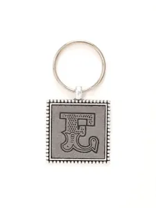 Detailed view of vintage decorative letter E embossed on silver square leather keychain