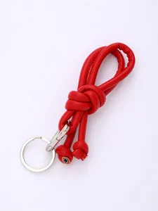 Macro detail of red knotted PU leather phone lanyard with durable silver metal ring