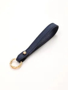 Detailed macro view of navy blue textured leather keychain strap with gold-tone hardware
