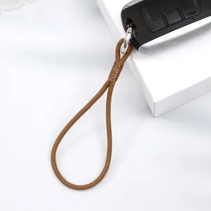 Detailed close-up of a handmade brown leather wrist strap attached to a car key fob