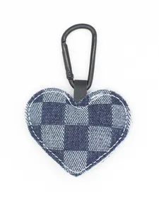 Detalle de un llavero de mezclilla en forma de corazón con un patrón de cuadros azul y blanco.