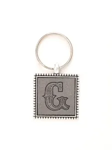 Macro view of embossed letter G on a vintage style square leather keychain