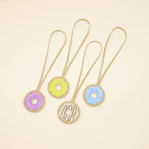 Close-up view of four colorful PU leather donut charms with long tan leather hanging loops.