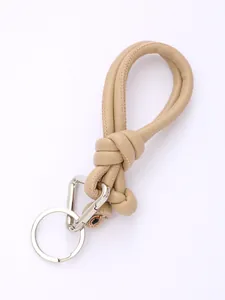 Detail of beige handmade PU leather braided lanyard with silver carabiner keychain.