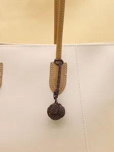 Detailed close-up showing a handmade polyester monkey fist knot charm attached to a bag