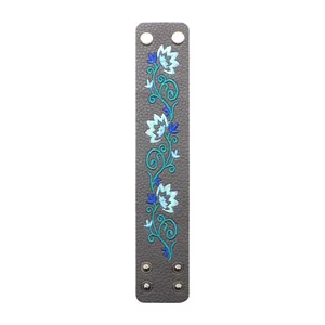 Detailed view of brown PU leather bracelet featuring blue and teal floral embroidery