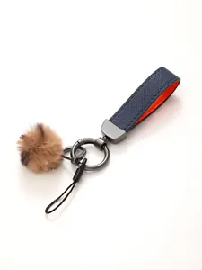 Detailansicht von marineblauem Leder-Schlüsselanhänger mit braunem Fellpompon